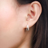 Fine jewellery, silver jewellery, hypoallergenic, tarnish-free, Close-up front view of an ear wearing a silver crystal hoop earring with dark hair and skin background